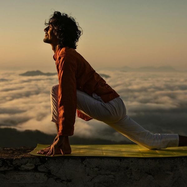 Silhouette of a person in a powerful yoga pose against a vibrant sunrise.
